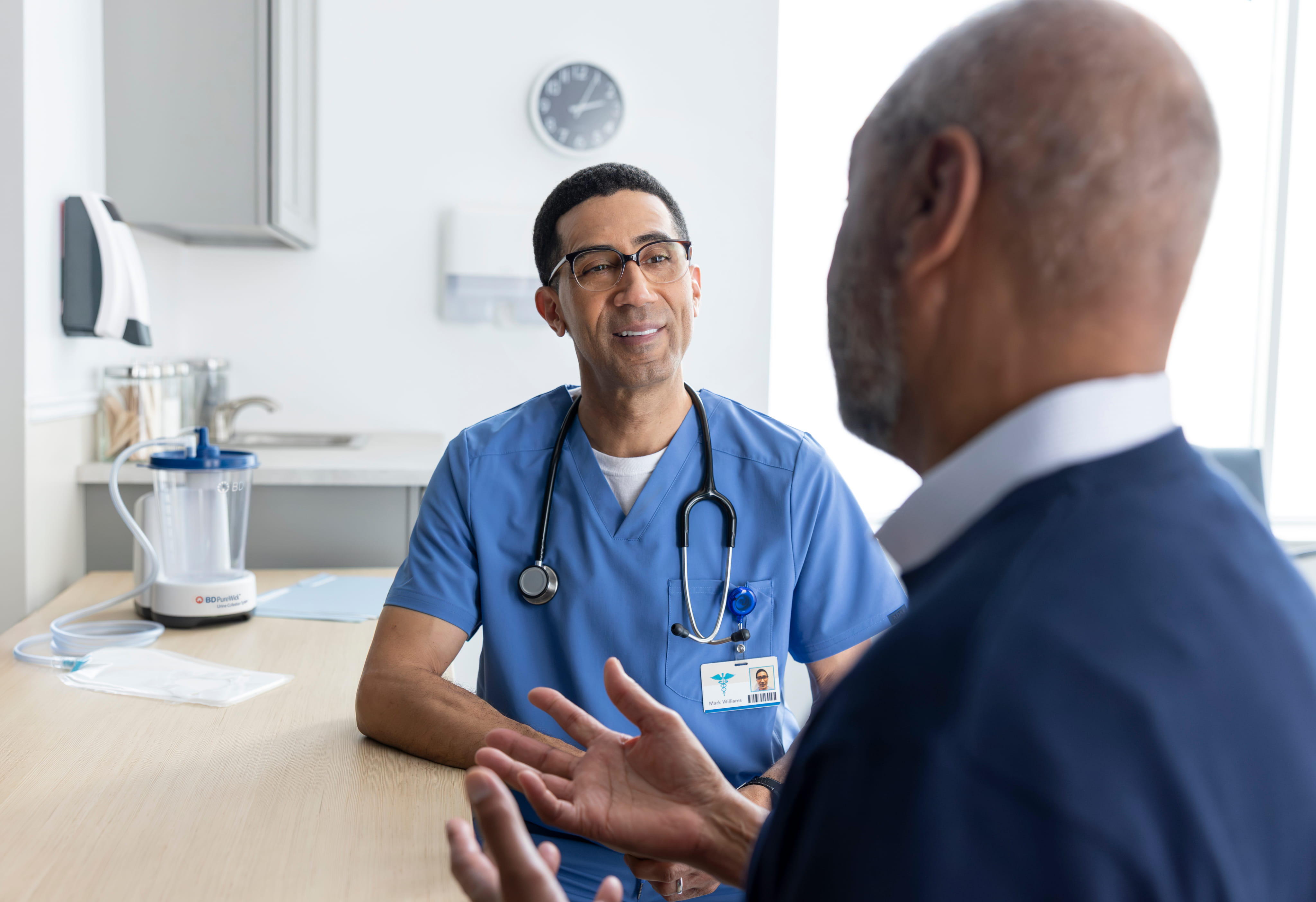 Healthcare provider and man talking in medical office with PureWick Collection System in background. 